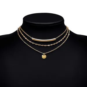 Detail of layered gold-plated necklaces with curved tube and round coin pendant