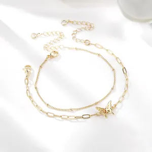 Detail van een 18K vergulde dubbellaagse armband met een elegante vlinderhanger