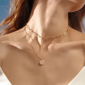 Detail of double-layered golden paperclip necklace with round letter A pendant on model
