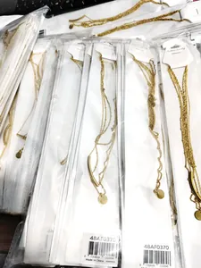Close-up of stacked gold multi-layer necklaces with tubes and round coin pendants