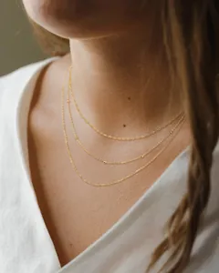 Detailed view of triple-layered gold stainless steel necklaces on a model neck
