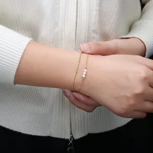 Elegante 18K vergulde dubbellaagse kettingarmband met 6mm parels om een vrouwenpols heen