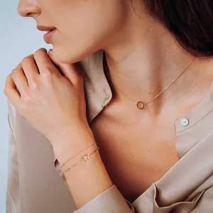 Detailweergave van een 18K goud dubbellaagse armband met oneindigheidssymbool en paperclipketting