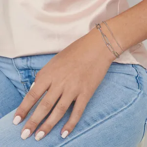 Detail van zilveren paperclip ketting en kralen armbanden op pols met zijde decor