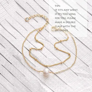 Detail van dubbellaagse gouden kettingarmband met witte parel en verstelbare verlenging