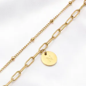 Detail van een 18K vergulde dubbele ketting met een geborstelde hanger letter N