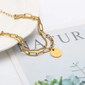 Detail van 18K vergulde dubbele kettingarmband met ronde hanger letter A