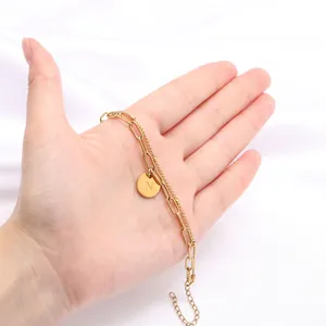 Detail van 18K vergulde dubbellaagse kettingarmband met een ronde hanger met letter N