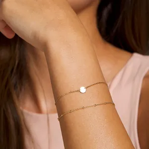 Gros plan du bracelet double chaîne en acier inoxydable plaqué or 18K avec médaillon