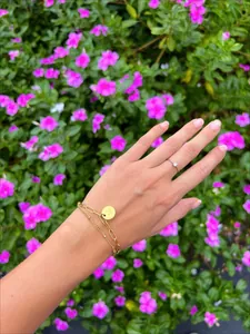 Detail van 18K gouden dubbellaagse armband met M-hanger en minimalistische ring met diamantje