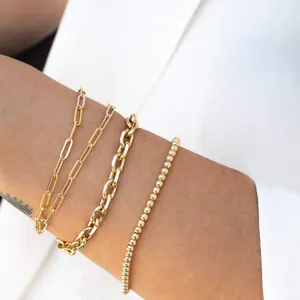 Dettaglio di quattro bracciali sovrapposti in acciaio inossidabile placcato oro 18K