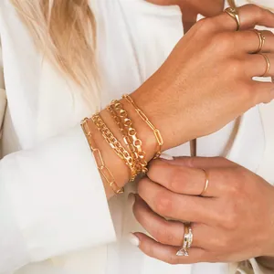 Dettaglio di bracciali a catena placcati oro 18K e anelli minimalisti indossati