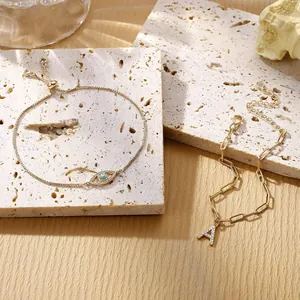 Gouden armbanden met Evil Eye en letter A-hanger op een minimalistische stenen plaat
