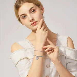 Detail van zilveren dubbele armbandset met paperclipketting en kraalvormige hanger