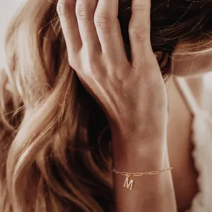 Detail van gouden paperclip ketting armband met micro-pave zirkoon letter M hanger