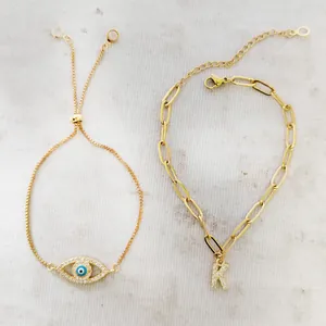 Detail van verstelbare gouden evil eye en kristallen letter K armbandenset
