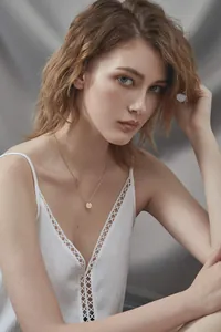 Detailed view of golden stainless steel necklace with a round G letter pendant on a model