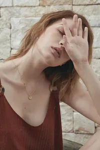 Detail of minimalist 18K gold letter I necklace worn by a model on casual knitwear