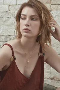 Detailed view of an 18K gold letter J pendant necklace on a model with warm lighting