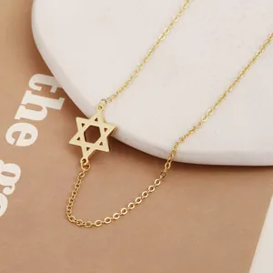 Detail shot of a minimalist gold Star of David pendant necklace on a stone display