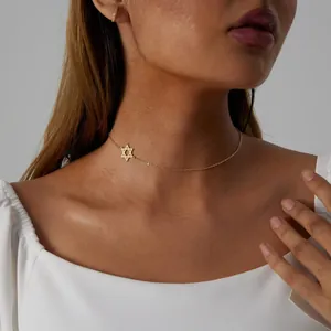 Close-up of a delicate gold Star of David pendant necklace on a model's neck
