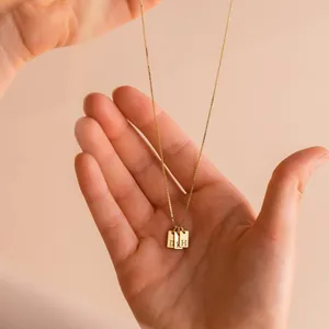 Nahaufnahme einer vergoldeten Edelstahlkette mit drei Mini-Anfangsbuchstaben-Anhängern
