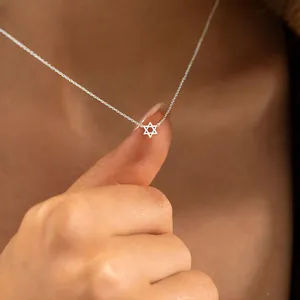Macro-opname van een kleine zilveren Davidster-hanger aan een fijne kruisketting