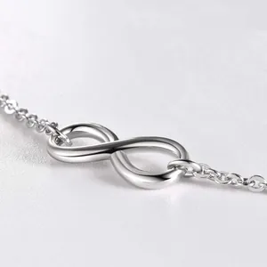 Macro shot of a polished silver infinity symbol pendant on a fine minimalist link chain
