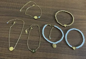 Detailed view of six 18K gold plated bead bracelets with heart and letter pendants