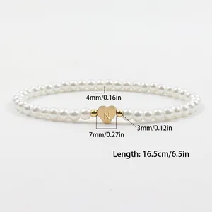 Faux pearl stretch bracelet with 18K gold heart charm featuring engraved letter N detail
