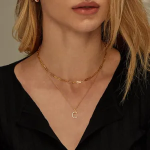 Close-up of gold paper clip layered necklace with sparkling zircon letter C pendant on neck