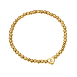 Close-up of gold-plated stainless steel bead bracelet featuring an engraved heart letter K charm