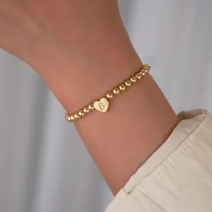 Detailed close-up of 18K gold-plated beaded bracelet with heart charm and letter B