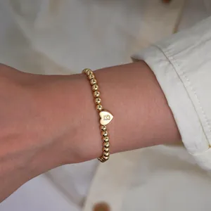 Detail of 18K gold-plated beaded bracelet featuring a heart charm with letter B engraving