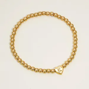 Macro view of 18K gold-plated beaded bracelet with a heart pendant engraved with letter K