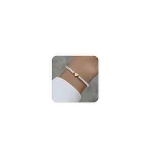 Close-up of pearl bead bracelet with heart charm engraved letter N on female wrist