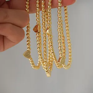 Detailed close-up of 18K gold-plated beaded heart bracelets with engraved letters