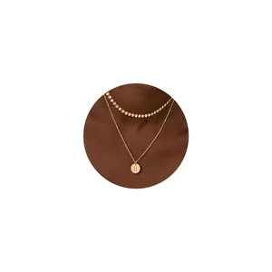 Detalle de collar de doble capa de oro de 18K con cadena de discos y colgante de la H