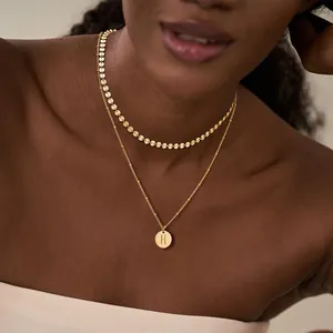 Detalle del collar de doble capa de oro de 18K con cadena de discos de 6mm y colgante letra H