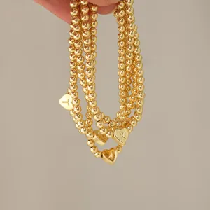 Detailed close-up of 18K gold-plated beaded bracelets featuring heart initial pendants