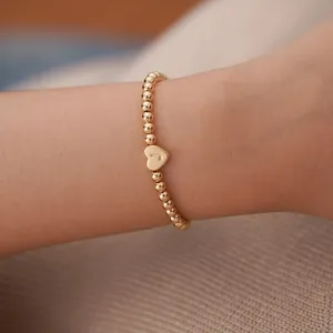 Detail of 18K gold-plated beaded bracelet featuring a heart charm with J engraving
