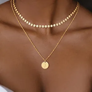 Primer plano de collar dorado de doble capa con gargantilla y colgante de letra J