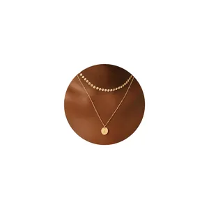 Detalle del collar de doble capa chapado en oro de 18K con discos Choker y colgante K