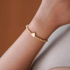 Detail of 18K gold-plated beaded bracelet with a heart pendant engraved with the letter J