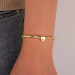 Detailed view of 18K gold plated bead bracelet with heart charm engraved with letter D