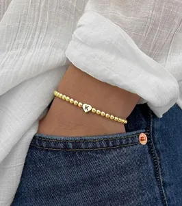 Detail of 18K gold beaded bracelet featuring a polished heart charm with letter K