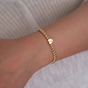 Close-up of 18K gold plated beaded bracelet featuring a heart charm with letter K
