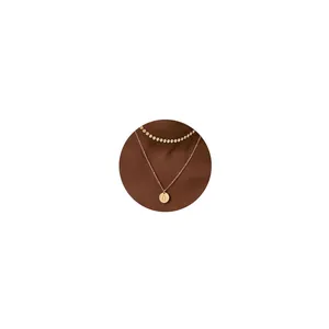 Detalle de collar de doble capa en oro de 18K con colgante redondo grabado con letra O