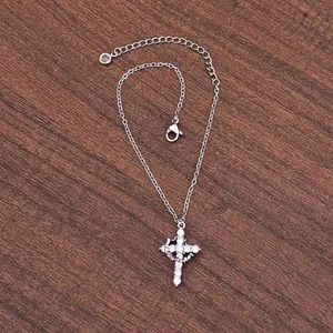 Macro shot of silver cross necklace with inlaid 3A zircons on a dark wood background