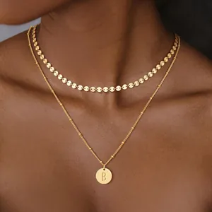 Detalle de collar de doble capa en acero inoxidable de 18K con colgante de la letra B